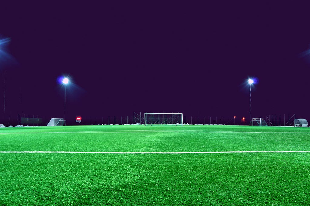 En belyst fotbollsplan en mörk kväll. Symbolik: SteadyGo jobbar med sportkommunikation.